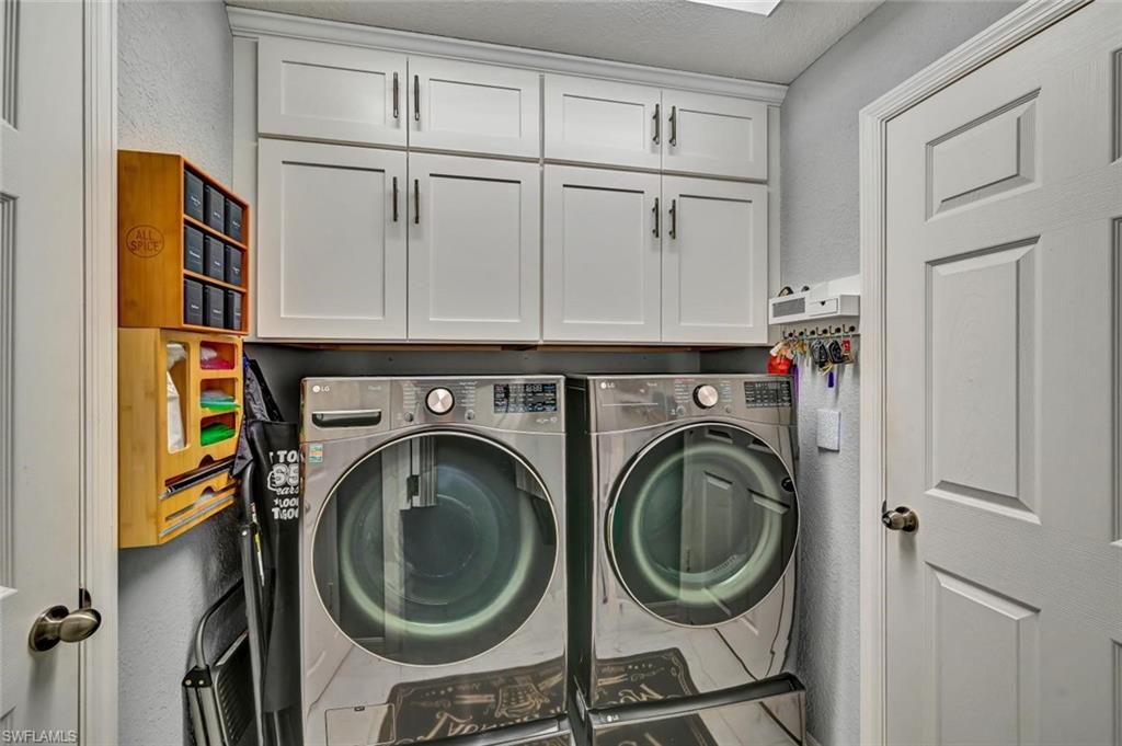 Laundry area featuring white shaker-style cabinetry with dark hardware and a built-in overhead light fixture