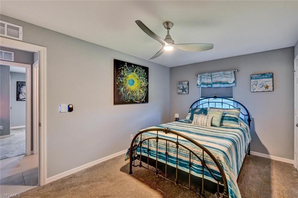 Carpeted room featuring a ceiling fan with integrated lighting, a window with a roller shade, and light gray wall paint