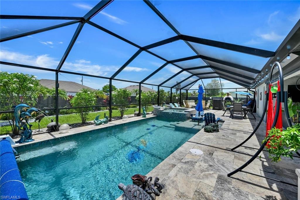 Screened outdoor living space featuring an in-ground pool with a spillover spa