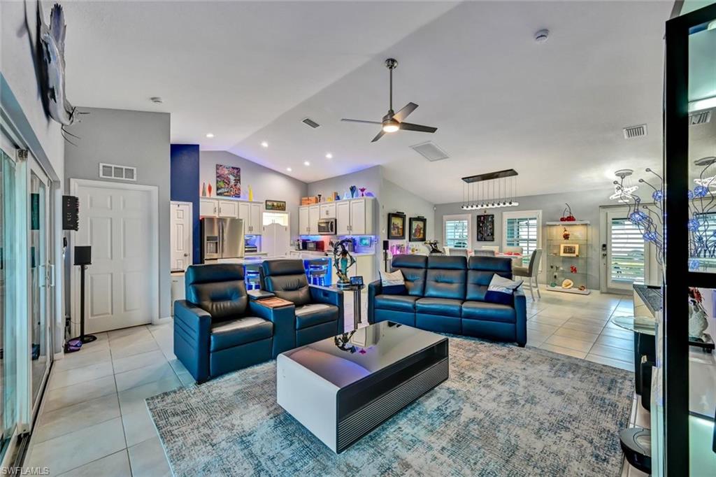 Expansive open-concept interior featuring vaulted ceilings, recessed lighting, and a neutral tile flooring throughout
