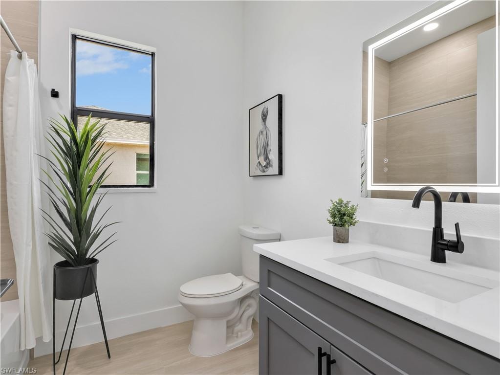 Bathroom featuring a contemporary gray vanity with a white countertop and integrated sink, a black waterfall faucet, and an illuminated mirror