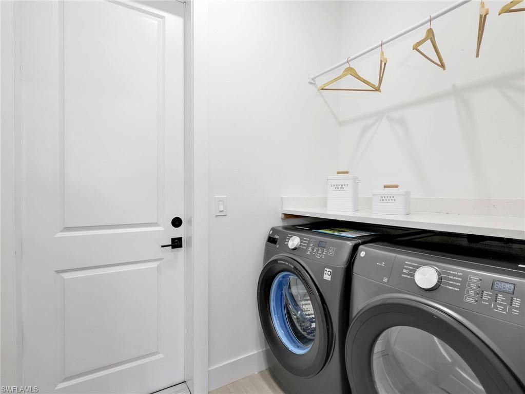 Dedicated laundry area featuring a white paneled door with black hardware, light-toned countertop, and an integrated hanging rod