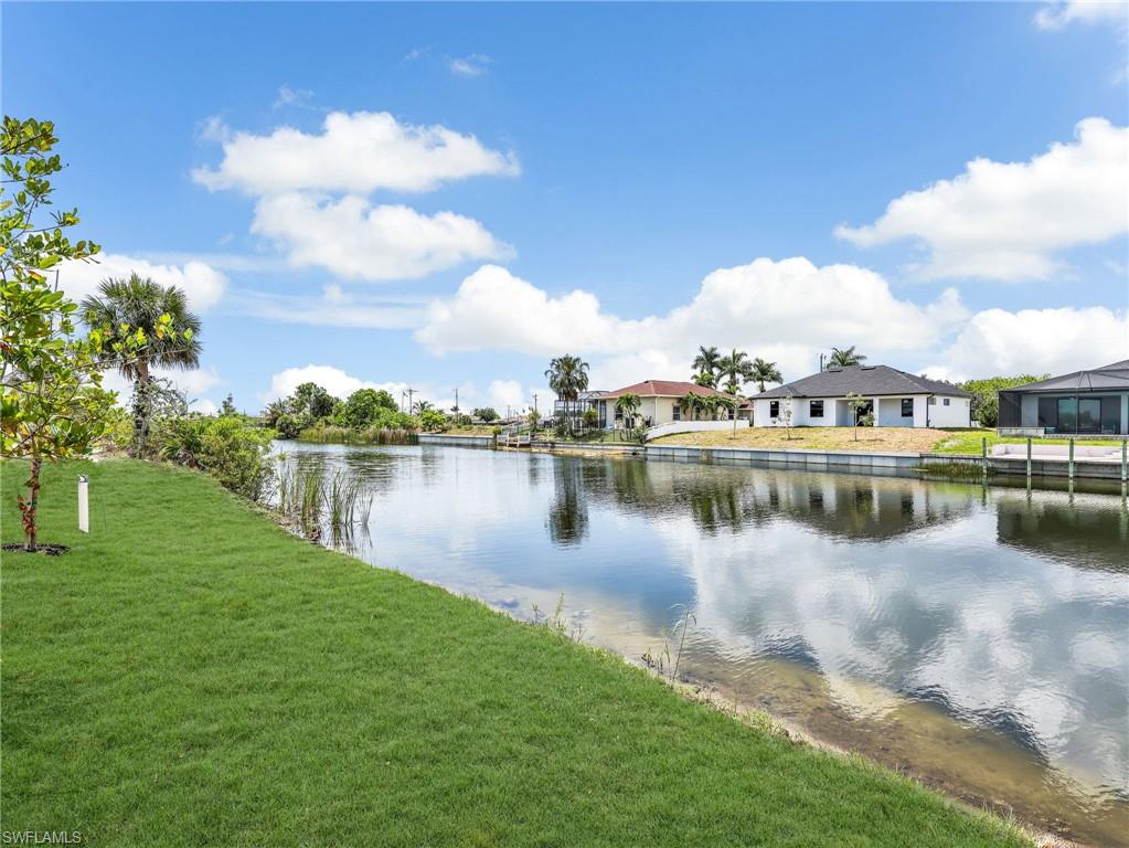 Waterfront property featuring a manicured lawn, lush tropical landscaping, and a freshwater canal