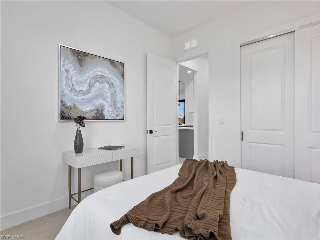Room featuring light-toned flooring, white walls, and a white sliding closet door with dark hardware