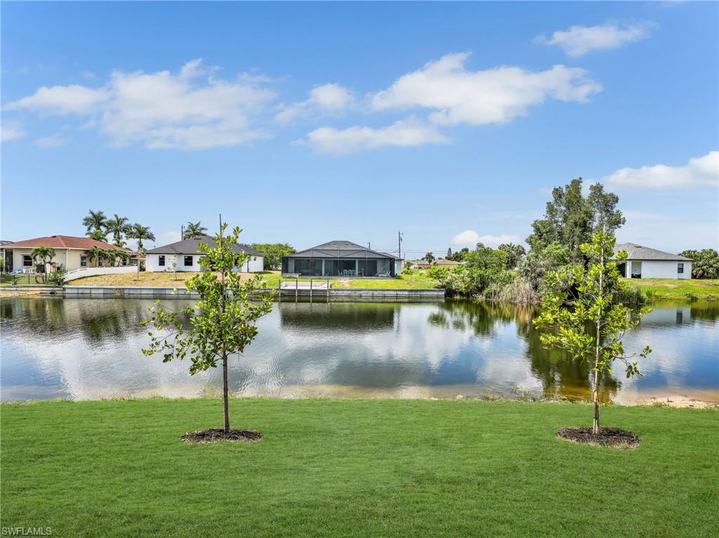 Expansive green lawn with two young trees, bordered by a tranquil body of water