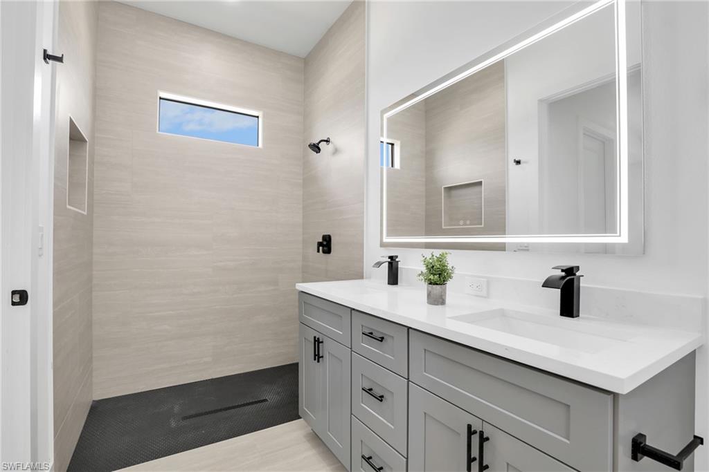 Modern bathroom featuring a dual vanity with light gray cabinetry, white countertops, and matte black fixtures