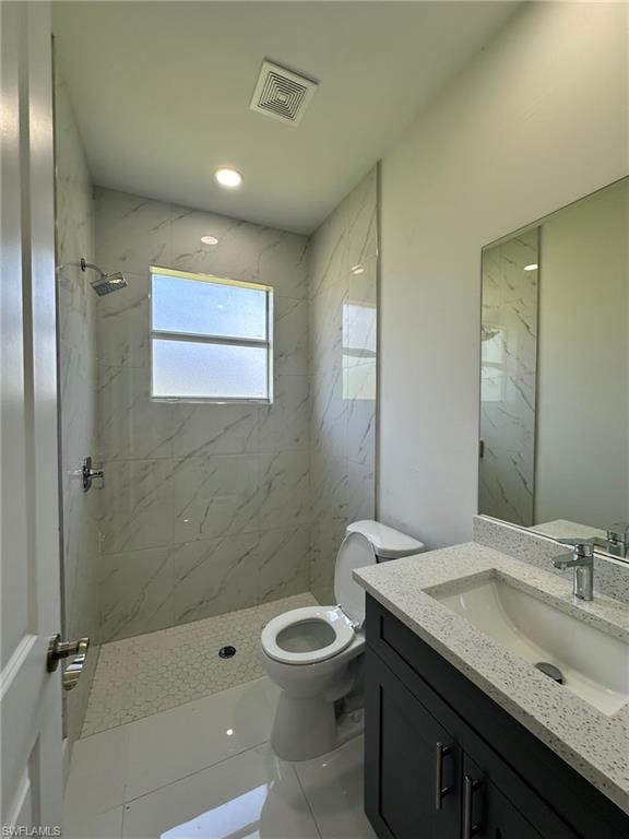 Bathroom featuring tile flooring, tiled shower, toilet, and large vanity