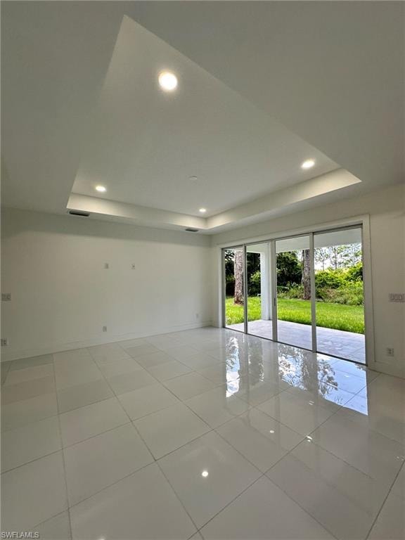 Spare room featuring a tray ceiling and light tile floors