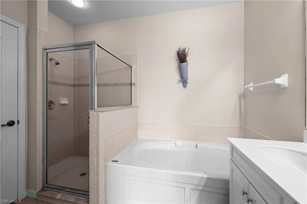Primary Full Bathroom featuring a garden tub, dual vanity, and a stall shower