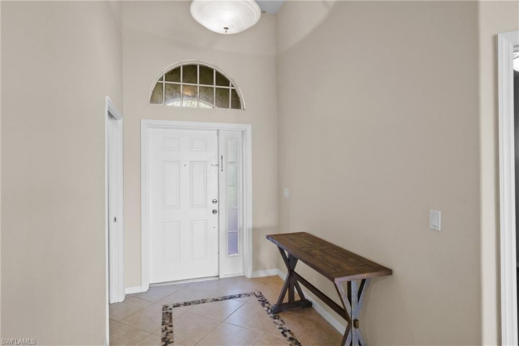 Foyer featuring light tile patterned flooring, inlaid floor details, and a high ceiling