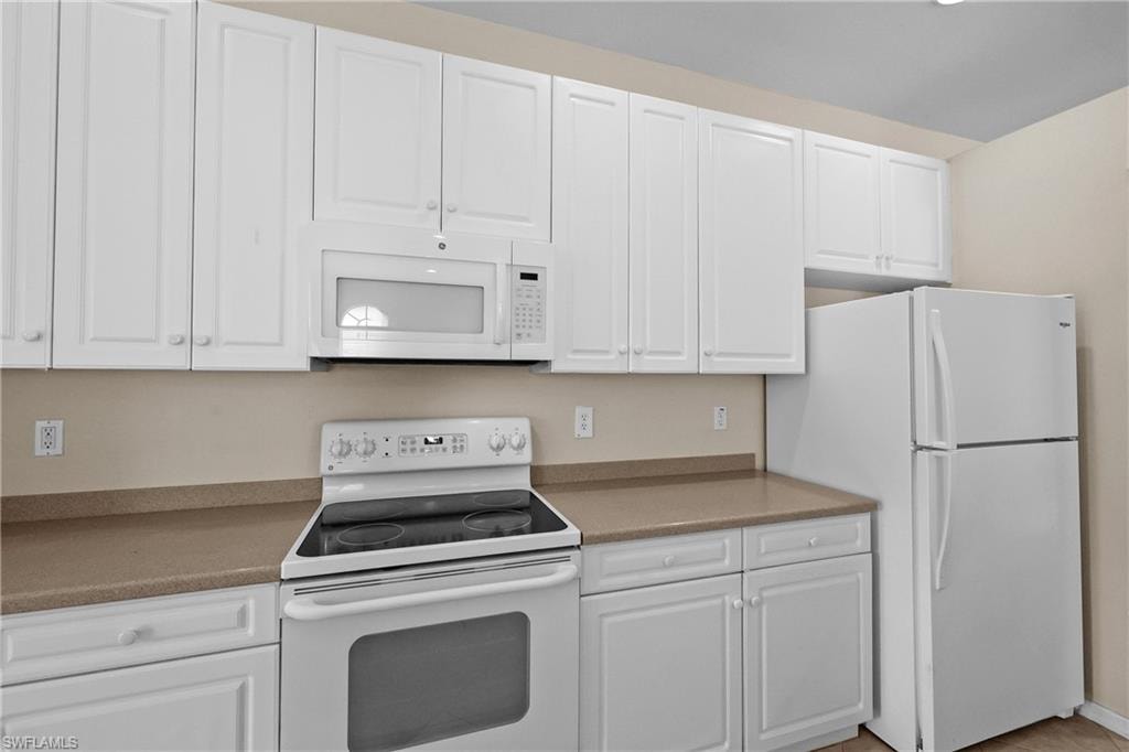 Kitchen featuring white appliances, white cabinets, and lots of counter space