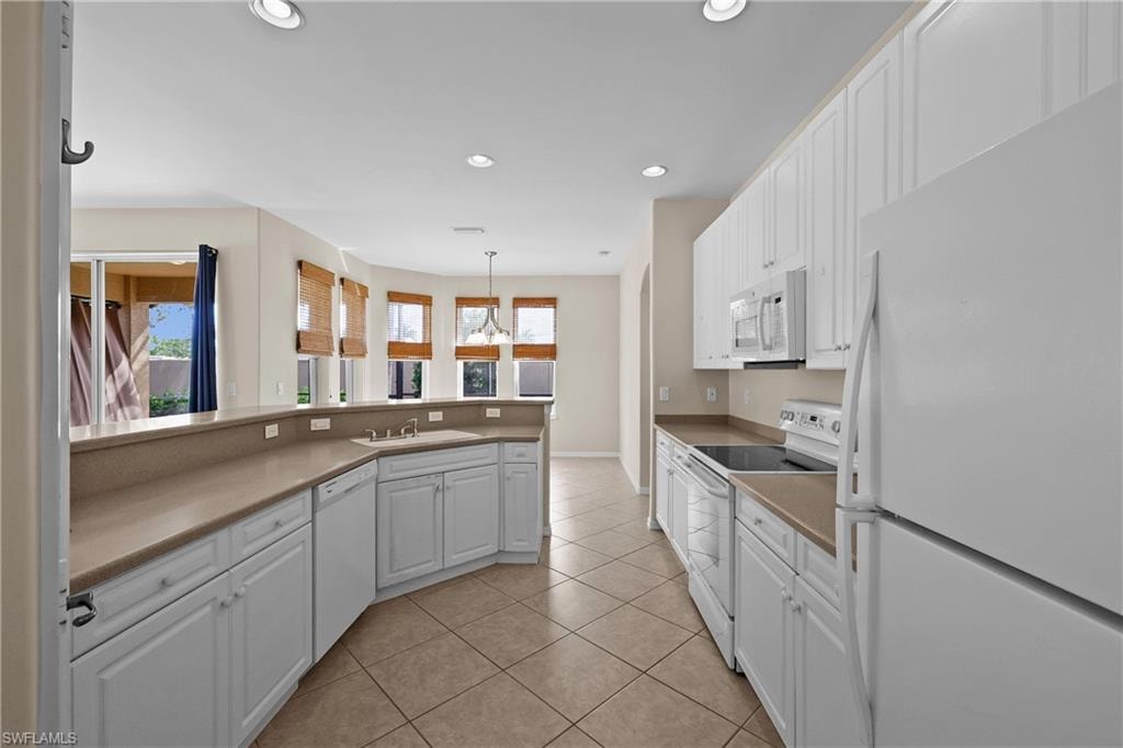 Kitchen featuring white appliances, white cabinetry, recessed lighting, light tile patterned flooring, and light countertops