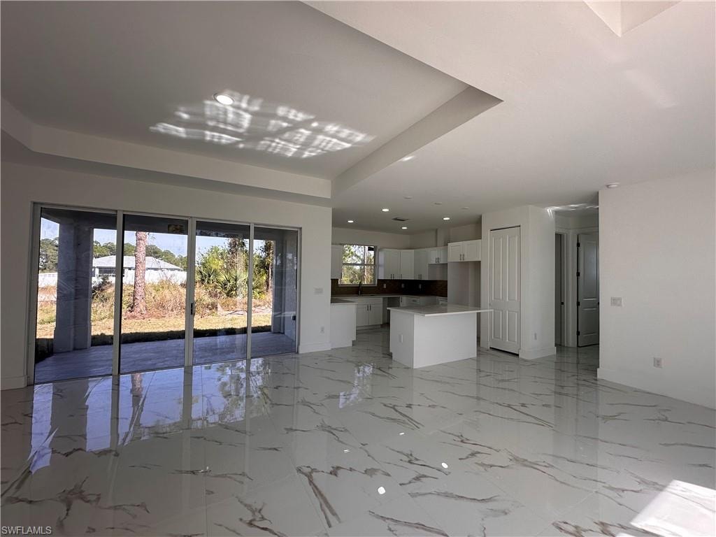 Unfurnished living room featuring a tray ceiling and sink