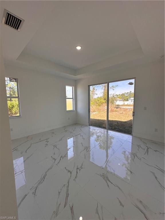 Empty room with plenty of natural light and a tray ceiling