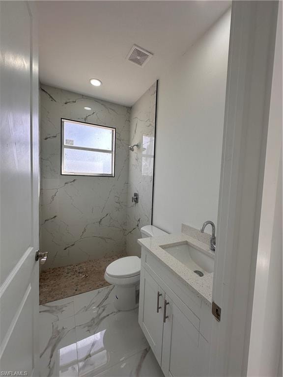 Bathroom with vanity, toilet, and tiled shower