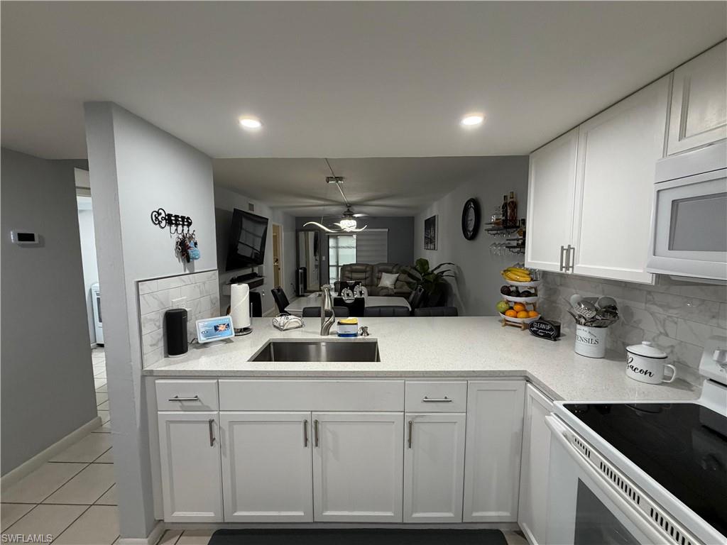 Modern kitchen featuring white shaker cabinetry, light-toned countertops, and a subway tile backsplash