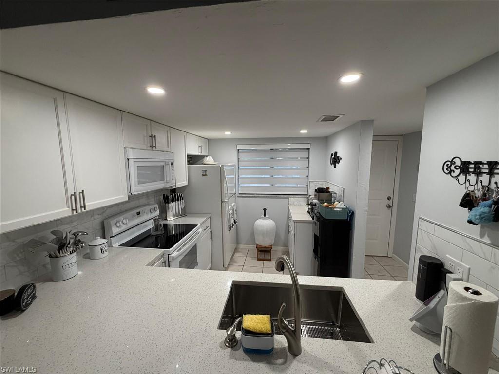 Modern kitchen featuring light-toned cabinetry, a stainless steel undermount sink, and light-colored countertops