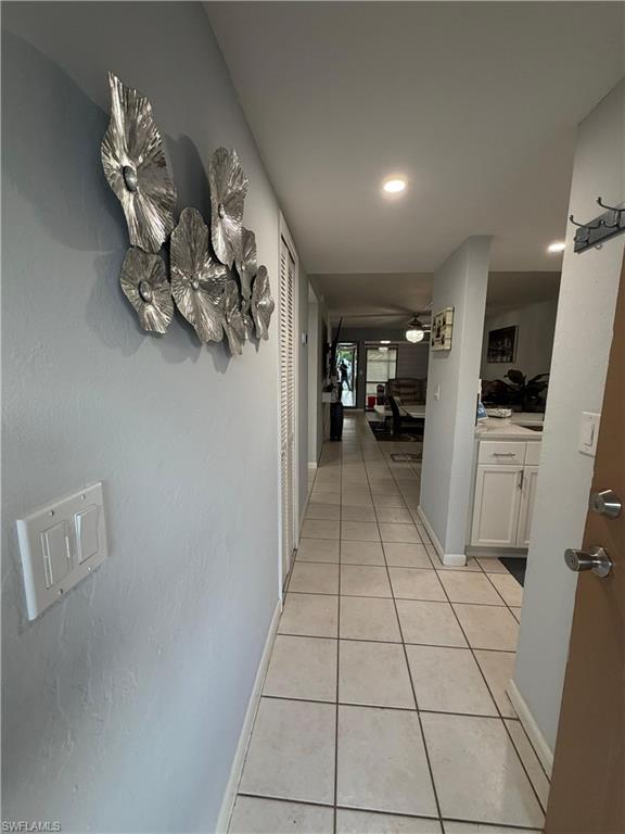 Hallway featuring square tile flooring and recessed lighting