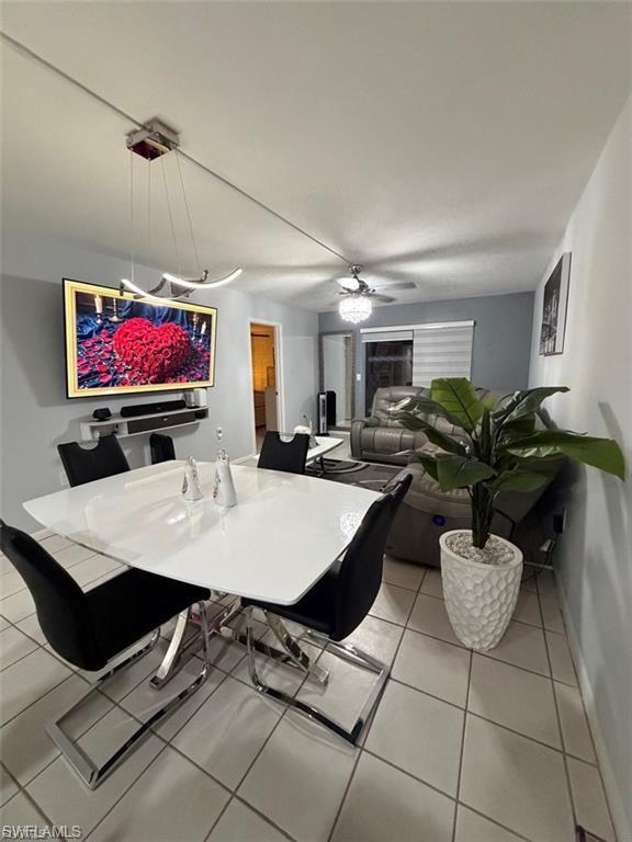Open-concept dining area featuring a contemporary chandelier, white tile flooring, and a modern dining table