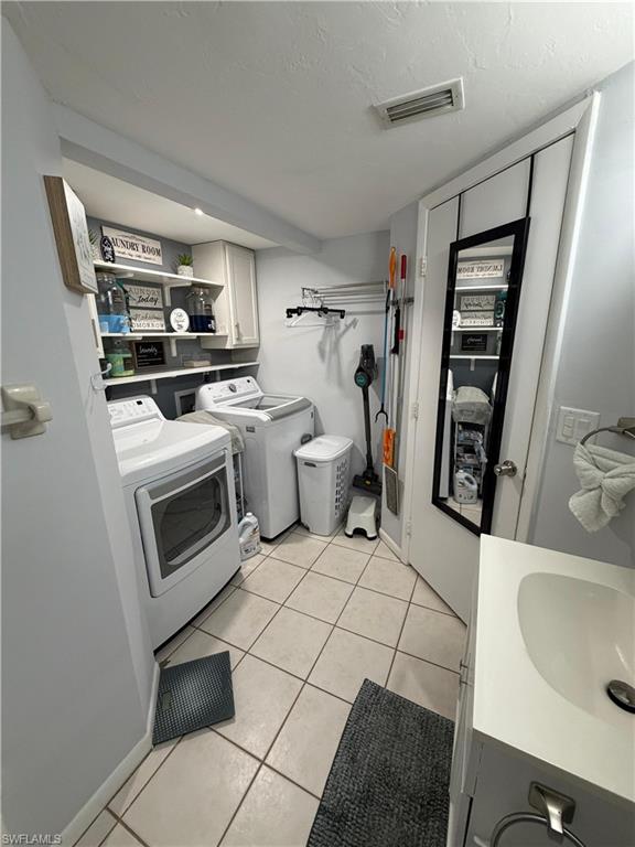 Utility room featuring a built-in vanity with an integrated sink, tiled flooring, and a dedicated laundry area with overhead cabinetry and shelving