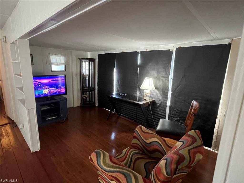 Living area featuring wood-finish flooring, a partial wall with integrated shelving.