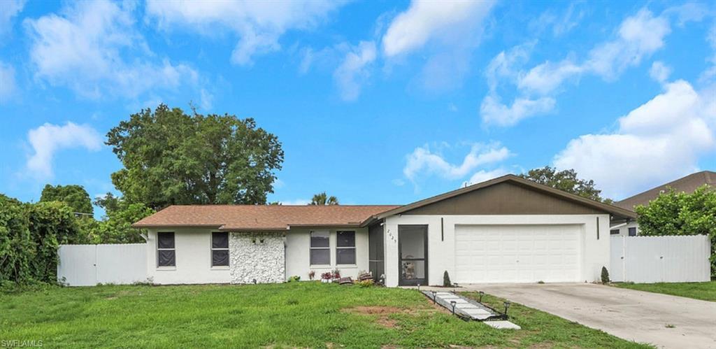 Ranch-style residence featuring a two-car garage, white facade, and a partial stone accent wall