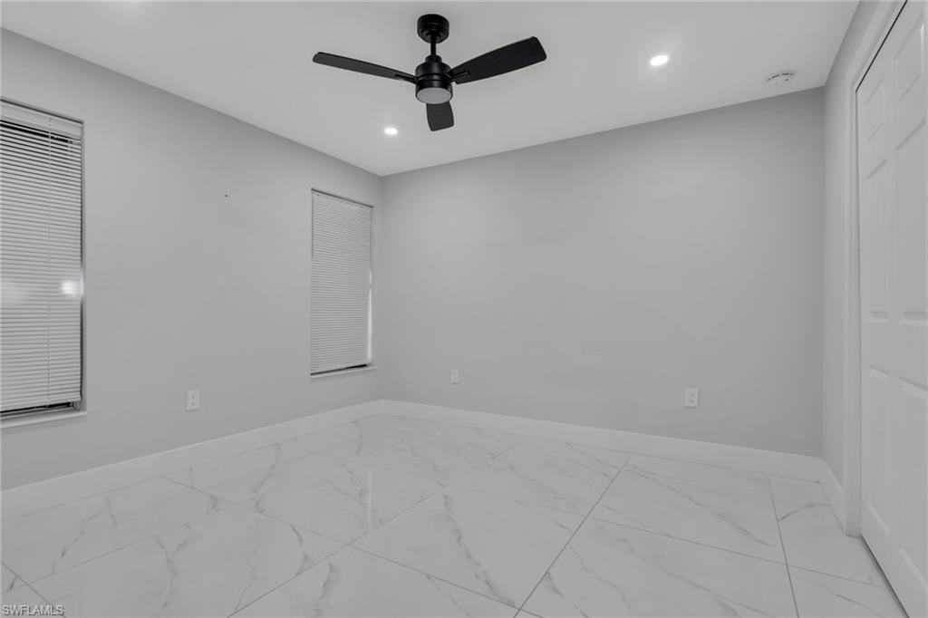 Spacious room featuring large format tile flooring, light gray walls, two windows with blinds, a ceiling fan, and recessed lighting