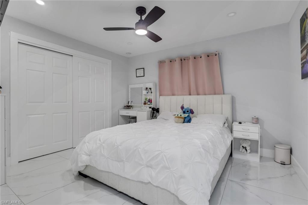 Bedroom featuring white tile flooring, a dark-toned ceiling fan with integrated lighting, and recessed ceiling lights