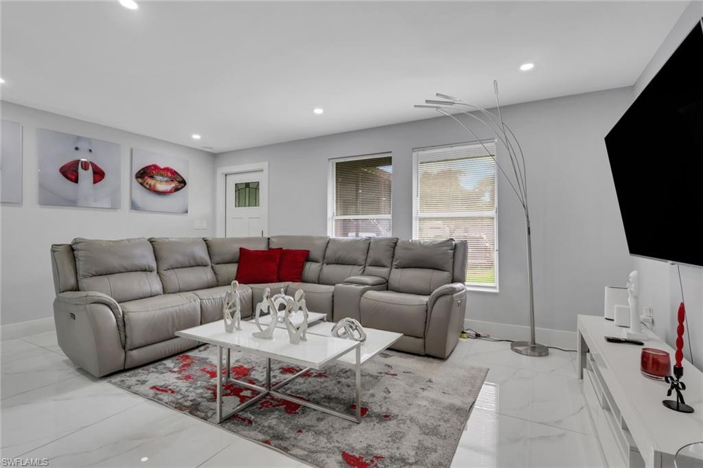 Living area with light gray walls, recessed lighting, white baseboards, and a white door with a clear glass insert