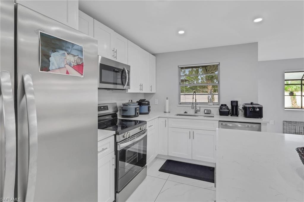 Modern kitchen featuring white cabinetry, stainless steel appliances, light-toned countertops, and recessed lighting