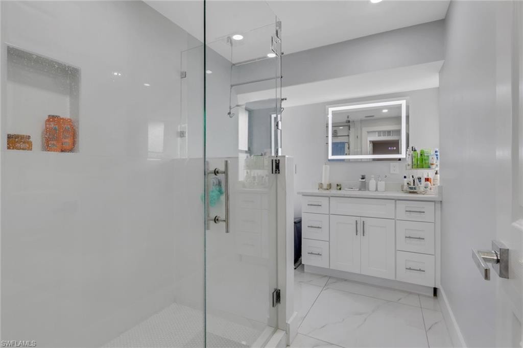 Modern bathroom featuring a frameless glass shower enclosure, a recessed shower niche, and white honeycomb mosaic tile flooring