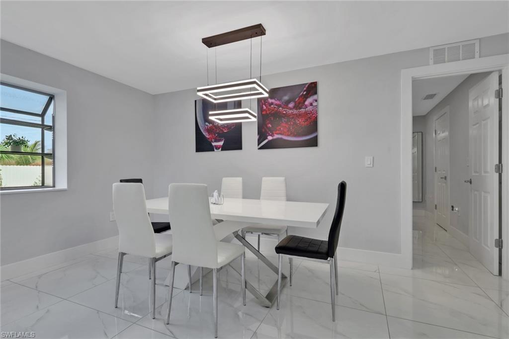 Modern dining space featuring a contemporary chandelier, light gray walls, and large format tile flooring