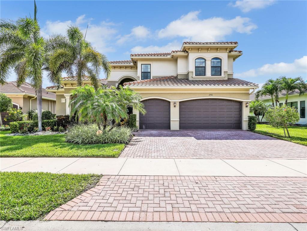 Stucco exterior with a tile roof, featuring an arched entryway, multiple arched windows, and a two-car garage with arched entrances