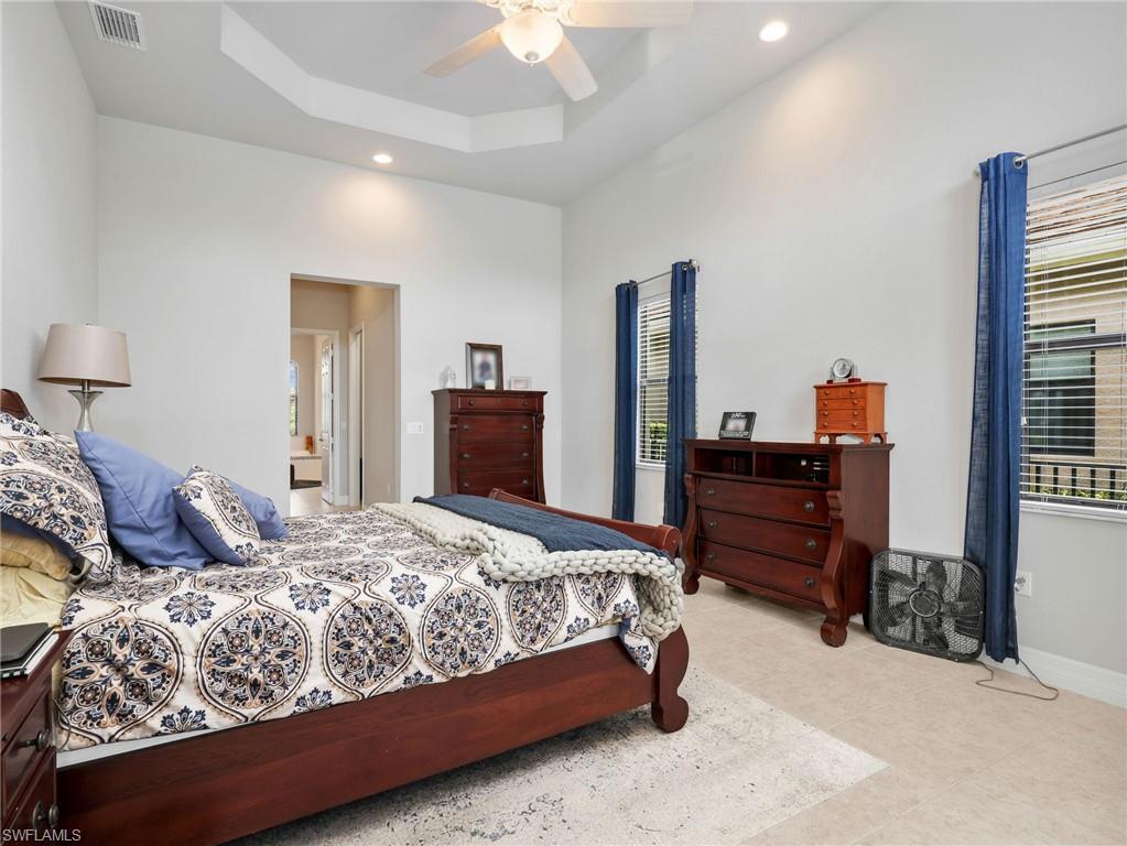 Spacious Master room featuring a tiered tray ceiling and tile flooring