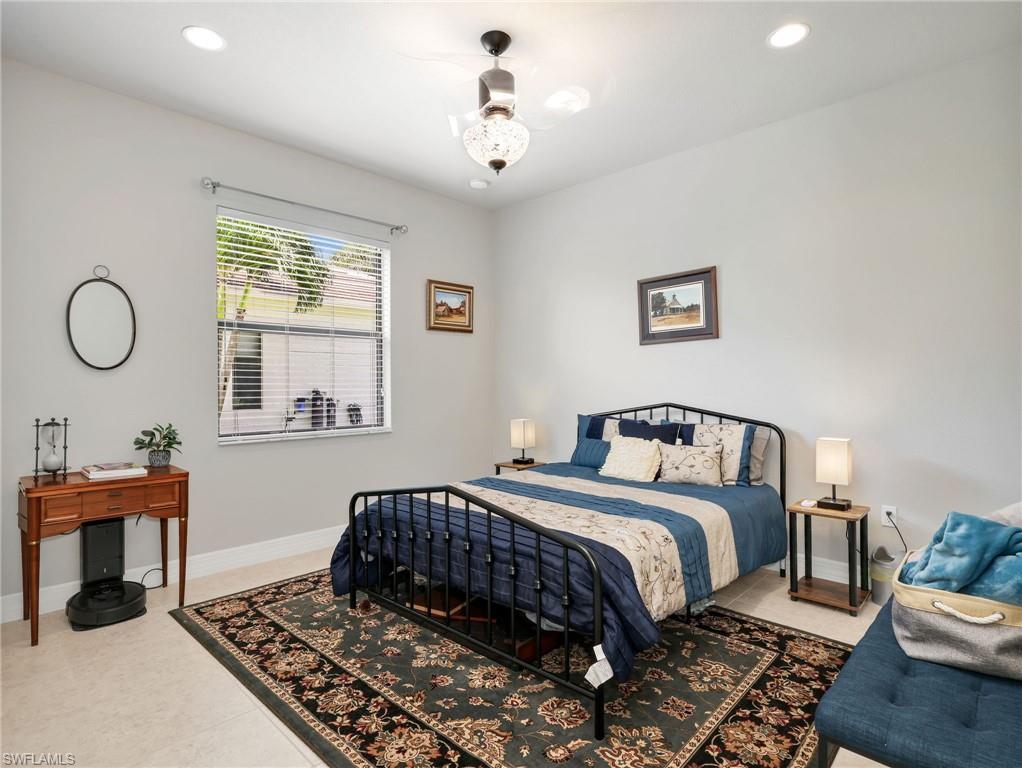 Spacious guest suite bedroom featuring recessed lighting, a ceiling fan with integrated light, tile flooring, and a large window with horizontal blinds