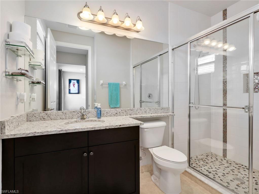 Bathroom featuring a dark wood vanity with a light speckled countertop, under-mount sink, and large wall-mounted mirror
