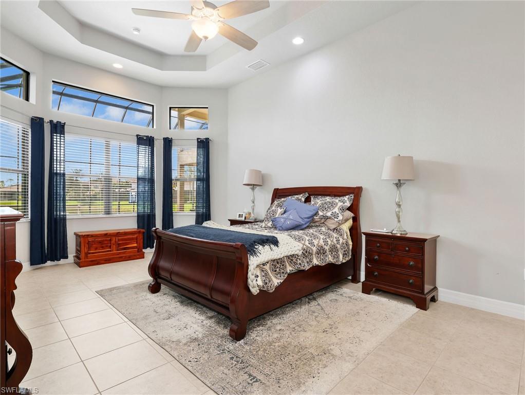 Spacious Master room featuring a tiered tray ceiling and tile flooring