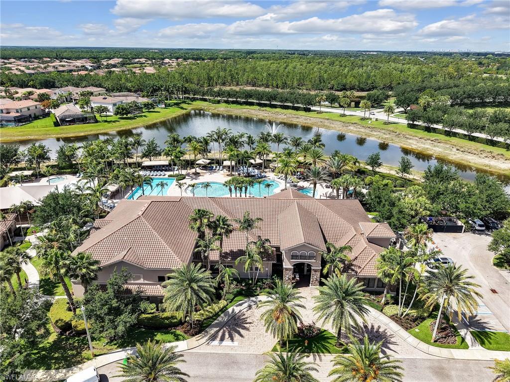 Community amenity building featuring a tile roof, multiple swimming pools, and extensive palm tree landscaping