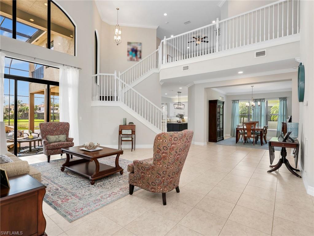 Grand living room with soaring ceilings, expansive two-story windows, and tile flooring