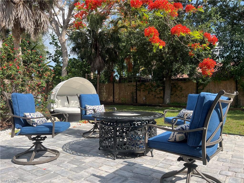 Paver patio featuring mature tropical landscaping and a vibrant flowering tree