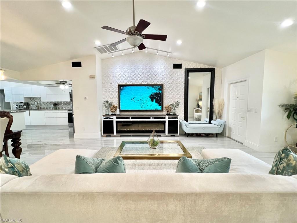 Spacious living area featuring a vaulted ceiling with a ceiling fan, recessed lighting, and large format tile flooring