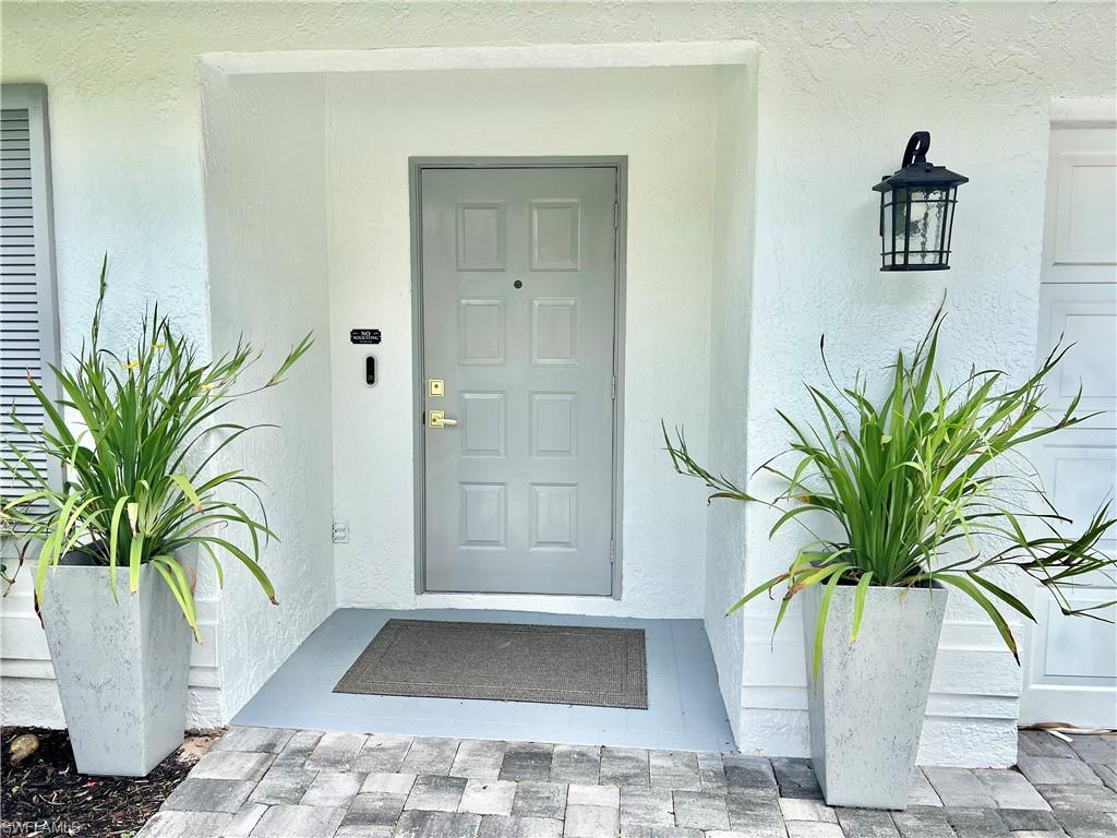 Entryway featuring a paneled door, exterior wall sconce, and paver walkway