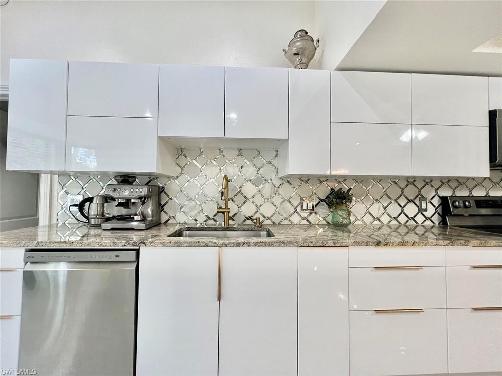 Modern kitchen featuring white high-gloss cabinetry with brass hardware, granite countertops, an arabesque tile backsplash, a stainless steel sink with a brass faucet, and a stainless steel dishwasher