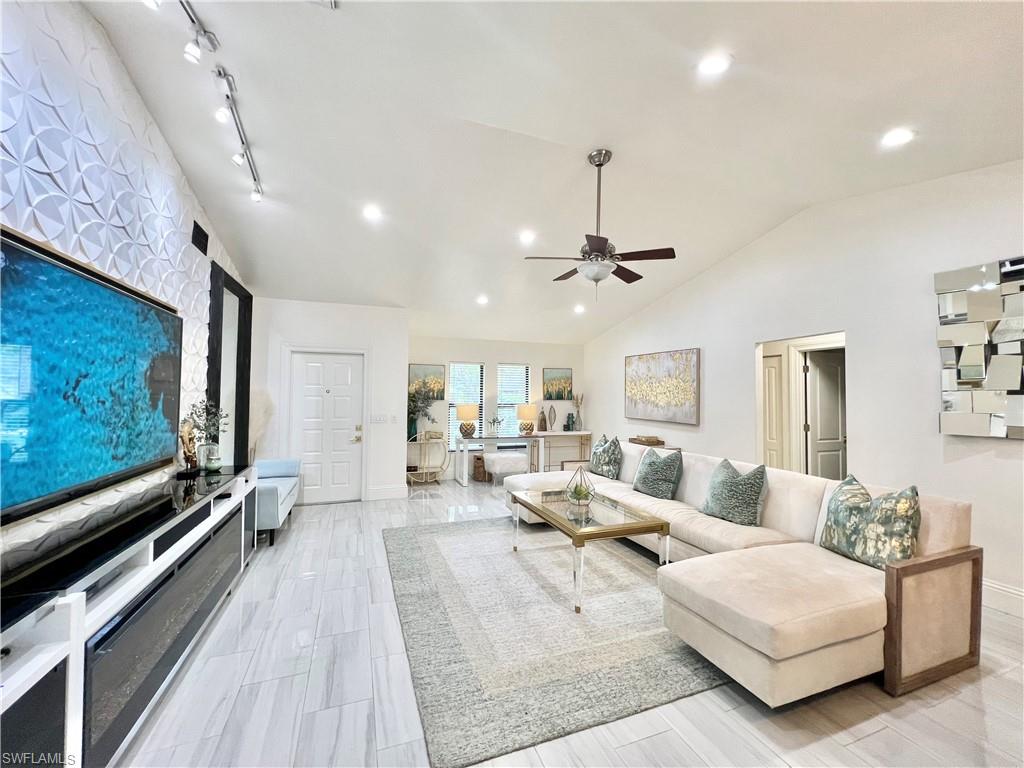 Vaulted ceilings enhance this living space featuring white walls and light-toned wood-finish flooring