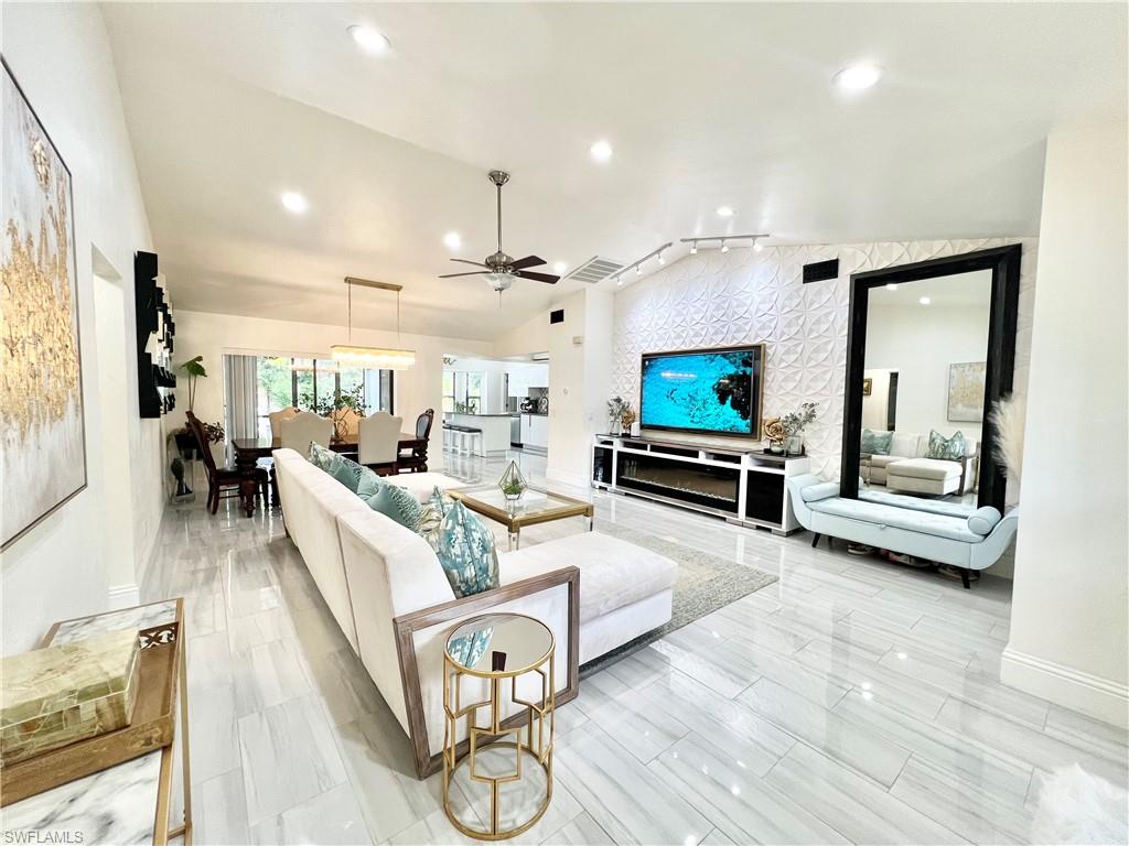 Expansive living area featuring vaulted ceilings, recessed lighting, and large format plank-style tile flooring