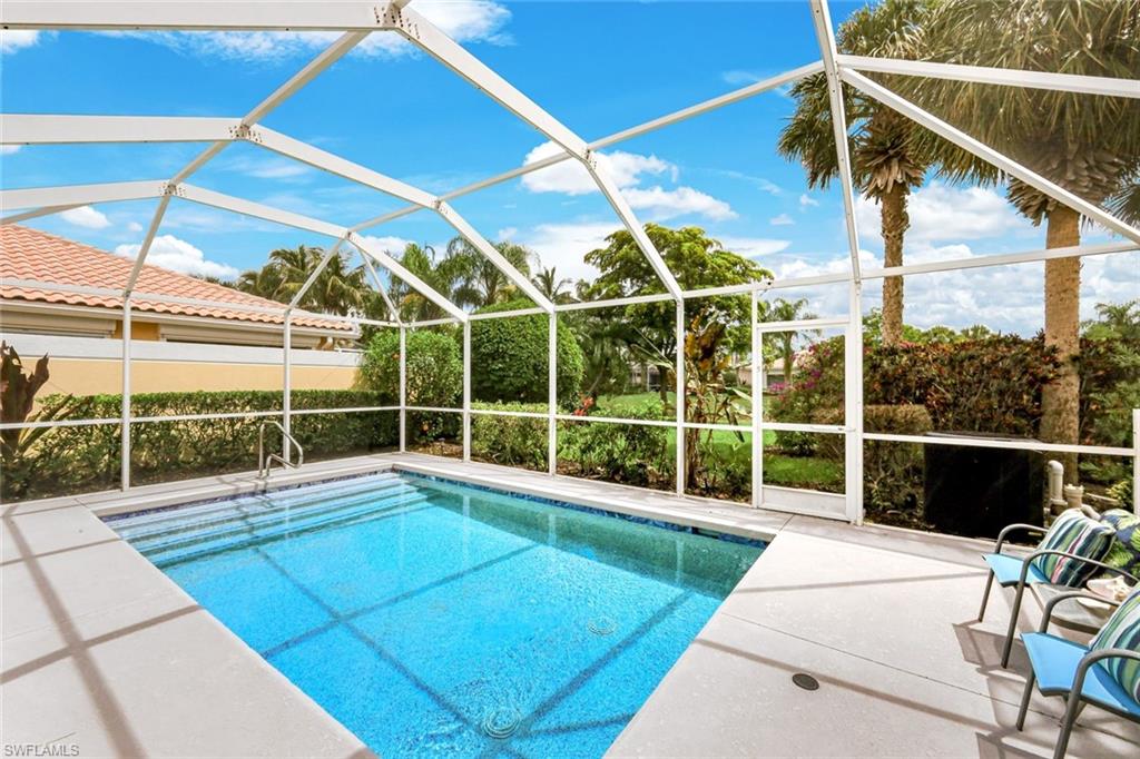 Screened pool enclosure featuring a rectangular pool with integrated steps, a paver pool deck, and lush tropical landscaping