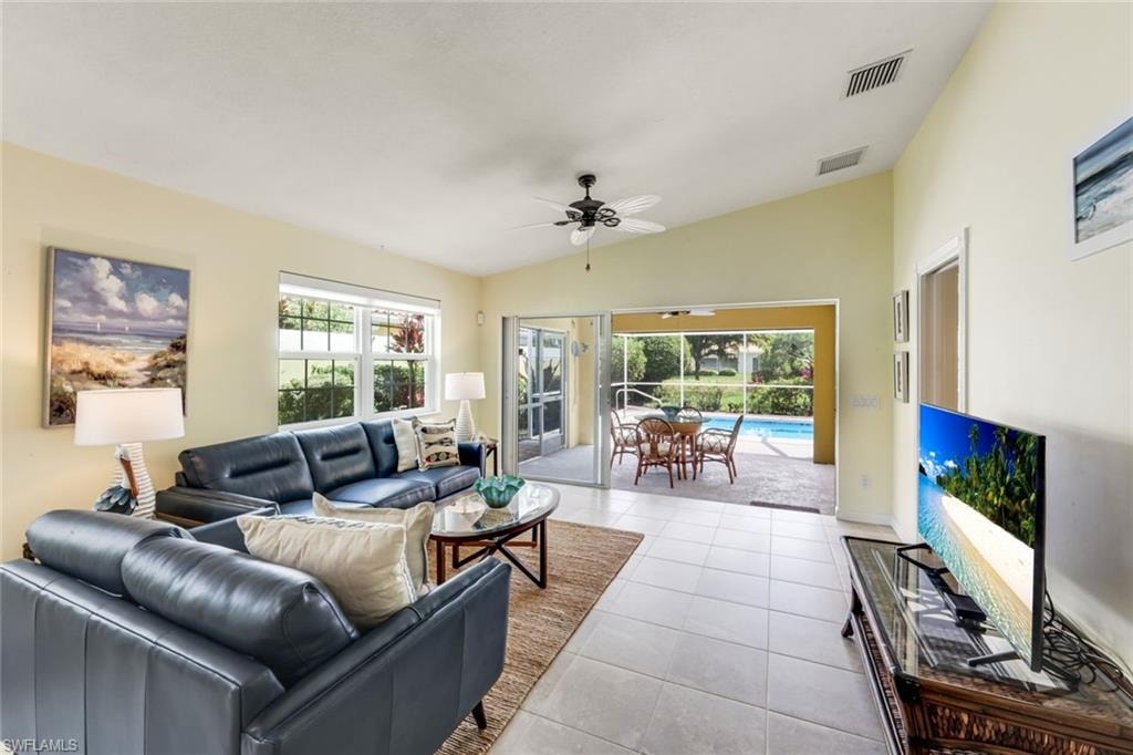 Living space featuring vaulted ceilings, tile flooring, and large windows