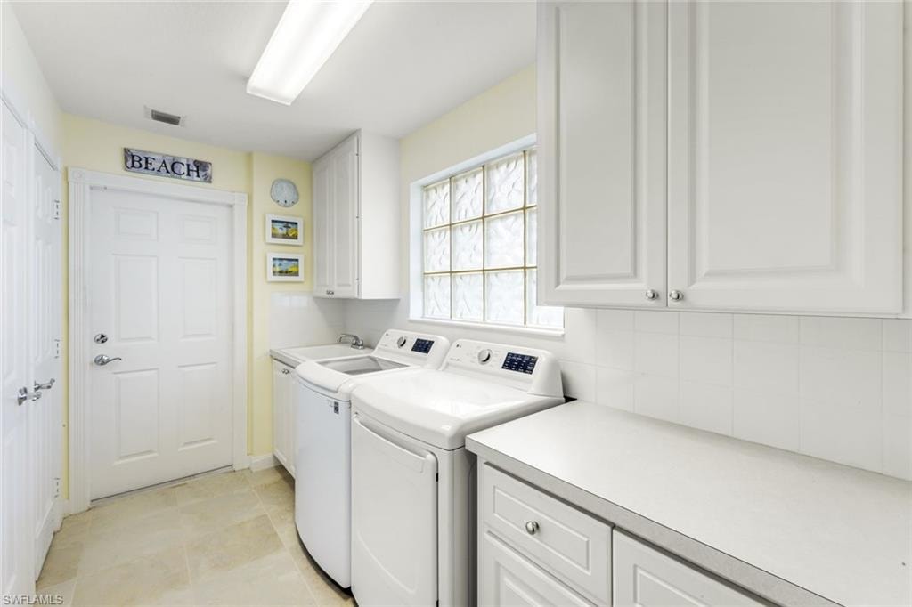 Dedicated utility space featuring ample white cabinetry, a glass block window, light-toned flooring, and a countertop with storage below
