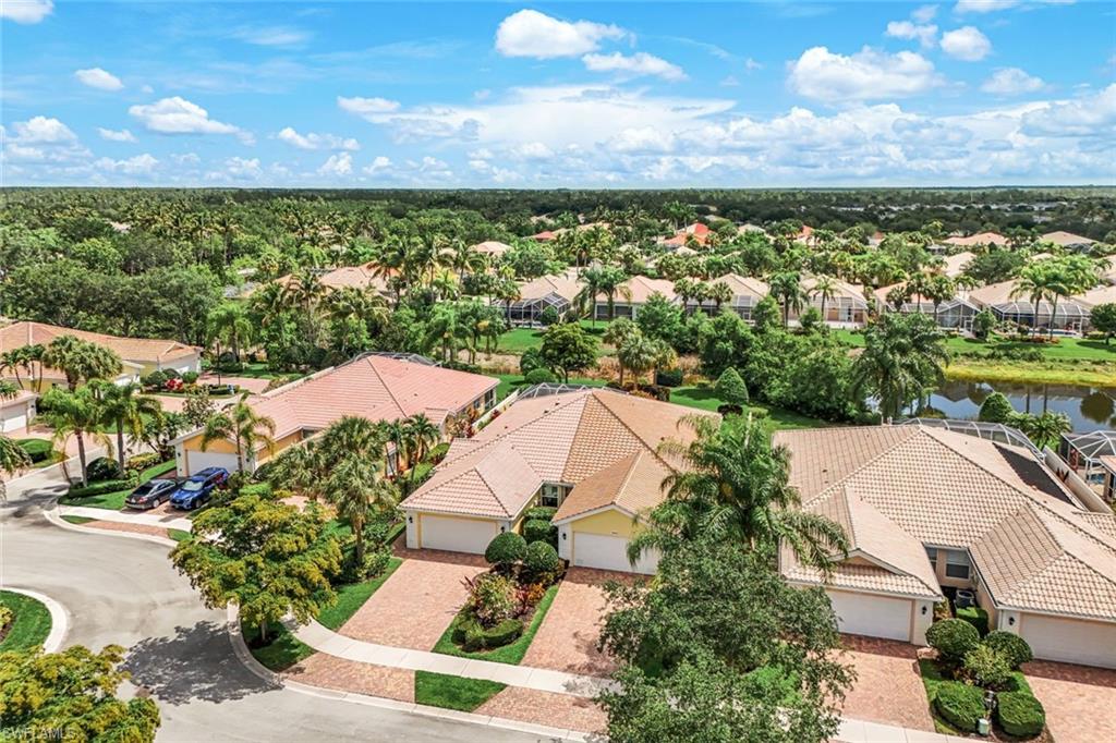 Aerial perspective showcasing a community of homes with tile roofs amidst lush tropical landscaping