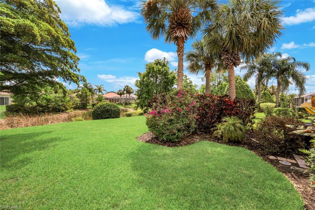Expansive green lawn with established landscaping, including multiple palm trees and flowering shrubs